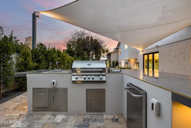 patio terrace at dusk featuring sink, grilling area, and an outdoor kitchen