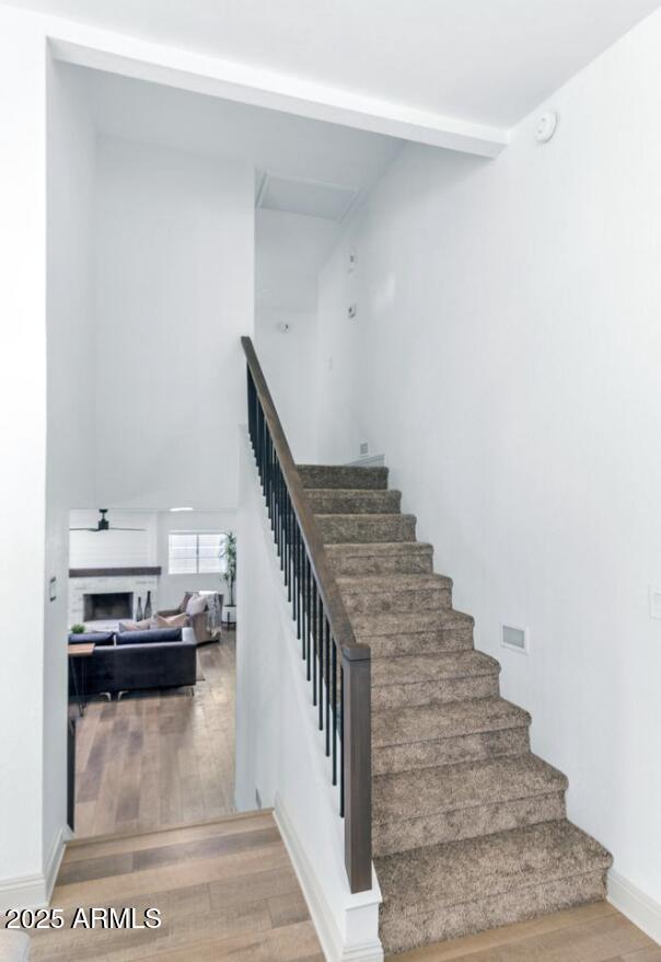 stairway featuring a towering ceiling, wood-type flooring, and beamed ceiling