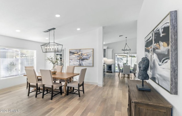 dining area featuring a notable chandelier, vaulted ceiling, and light wood-type flooring