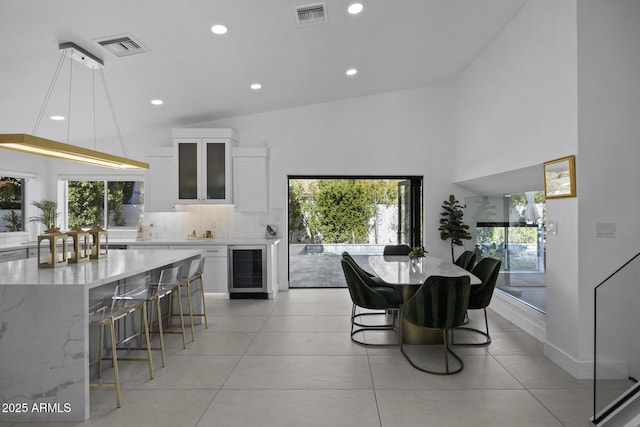 tiled dining room with wine cooler and a high ceiling