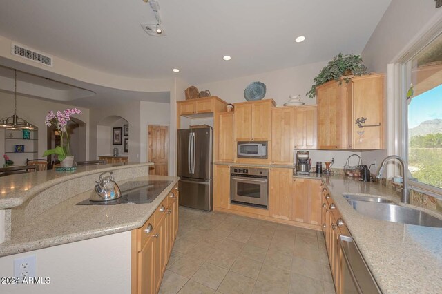 kitchen featuring stainless steel appliances, light tile flooring, light stone counters, hanging light fixtures, and sink