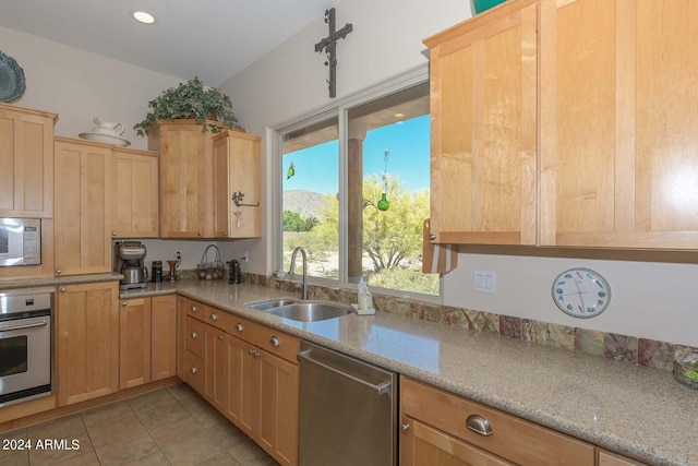 kitchen with sink, light stone countertops, light tile floors, and stainless steel appliances