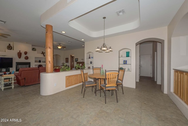 dining room featuring tile flooring, ceiling fan with notable chandelier, and a tray ceiling