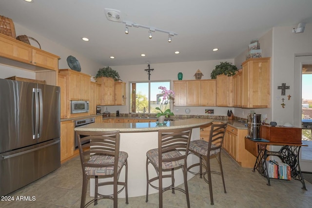 kitchen with a center island, stainless steel appliances, a breakfast bar, sink, and light tile floors