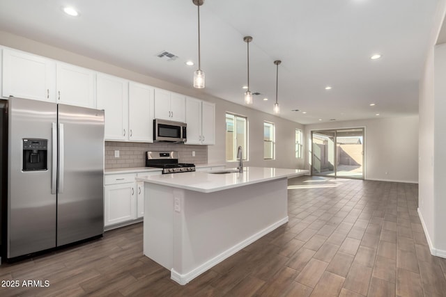 kitchen with sink, white cabinetry, hanging light fixtures, appliances with stainless steel finishes, and a kitchen island with sink