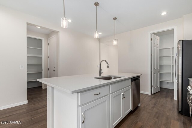 kitchen featuring appliances with stainless steel finishes, pendant lighting, white cabinetry, sink, and a center island with sink