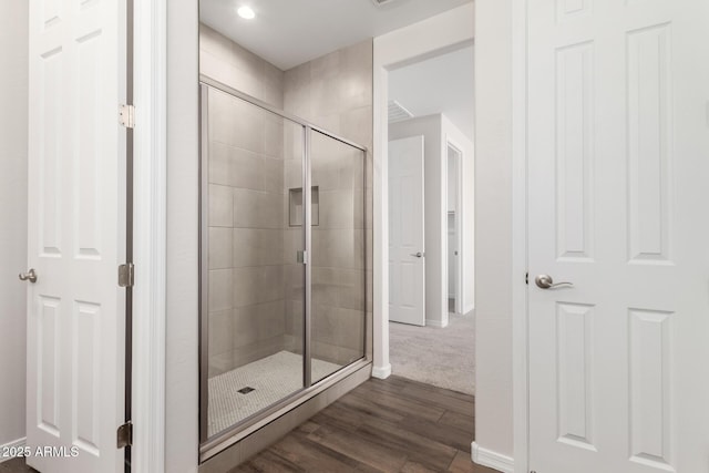 bathroom with hardwood / wood-style flooring and a shower with shower door