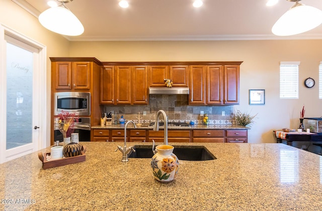 kitchen with light stone counters, stainless steel appliances, ornamental molding, and sink