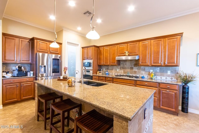 kitchen featuring appliances with stainless steel finishes, decorative light fixtures, a kitchen island with sink, and tasteful backsplash