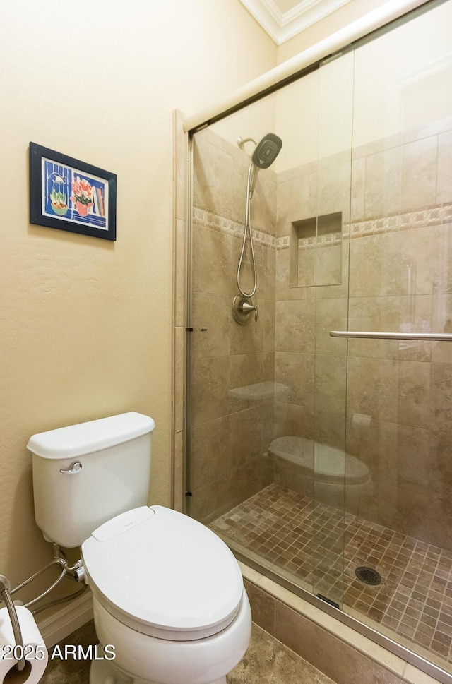 bathroom with toilet, a shower with door, and crown molding