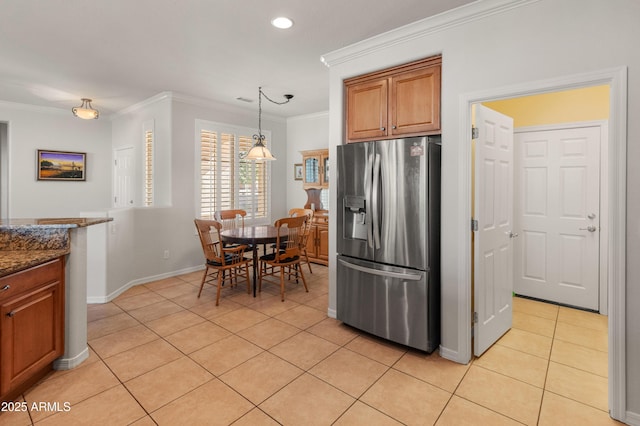 kitchen with decorative light fixtures, dark stone counters, light tile patterned floors, stainless steel fridge with ice dispenser, and crown molding