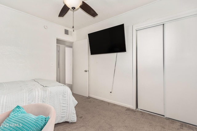 carpeted bedroom with crown molding, ceiling fan, and a closet