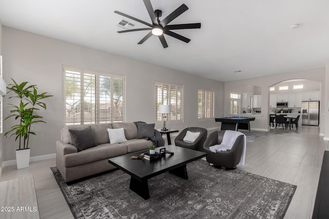 living area featuring visible vents, baseboards, ceiling fan, arched walkways, and billiards