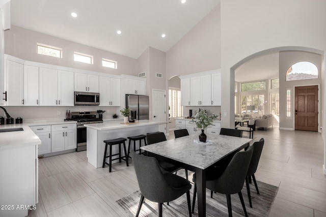 dining area with arched walkways, high vaulted ceiling, visible vents, and recessed lighting
