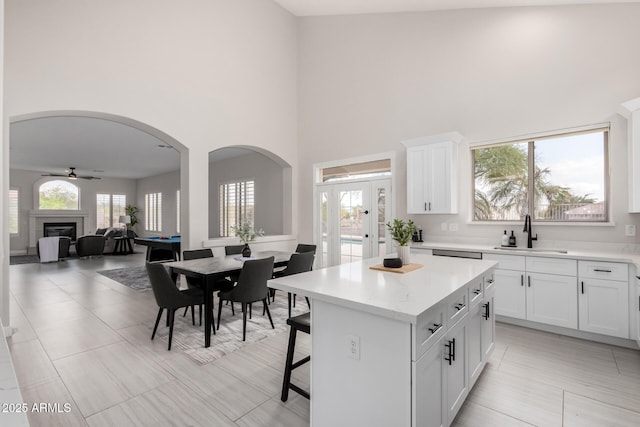 kitchen featuring a sink, a kitchen breakfast bar, arched walkways, a glass covered fireplace, and a kitchen island