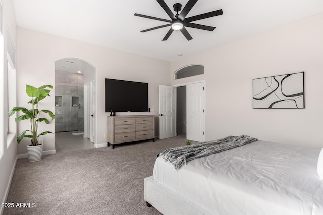 bedroom featuring carpet flooring, arched walkways, a ceiling fan, connected bathroom, and baseboards