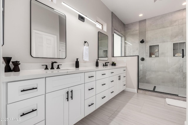 bathroom with recessed lighting, double vanity, a walk in shower, and a sink