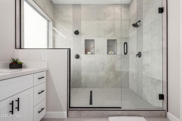 full bath with vanity, baseboards, and a shower stall