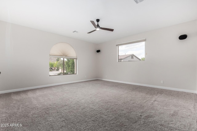 spare room with a ceiling fan, baseboards, visible vents, and plenty of natural light