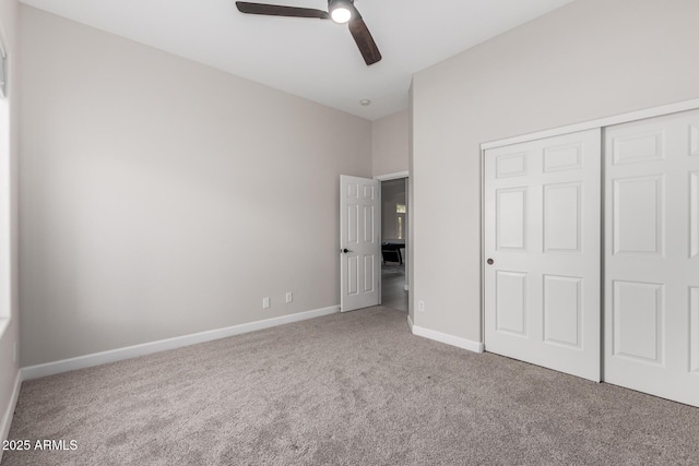 unfurnished bedroom with carpet, a closet, baseboards, and ceiling fan