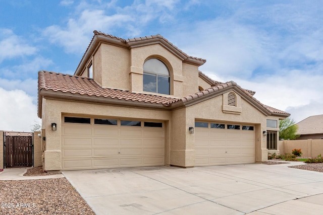 mediterranean / spanish-style house featuring fence, driveway, a garage, stucco siding, and a tiled roof