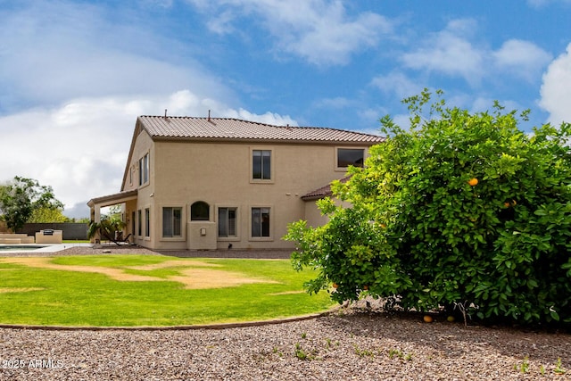 rear view of property with a tiled roof, a yard, and stucco siding