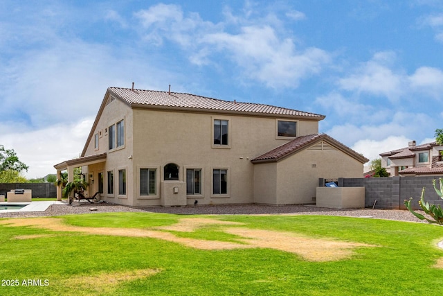 back of property with a lawn, stucco siding, a tiled roof, and a fenced backyard