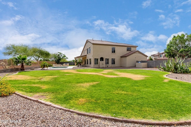 rear view of property featuring a tile roof, stucco siding, a fenced backyard, a jacuzzi, and a lawn