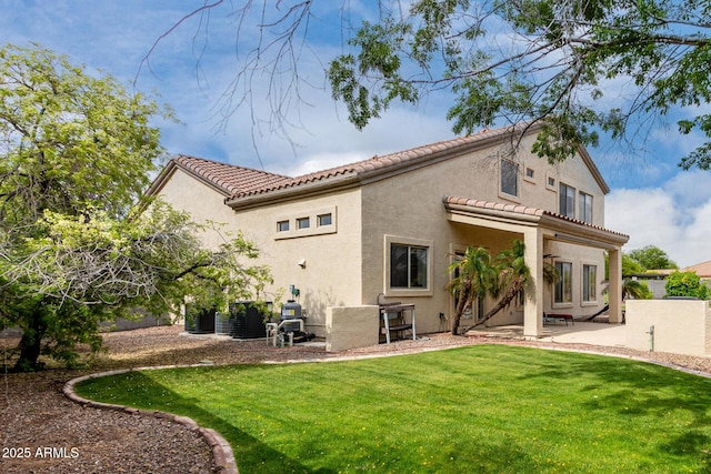 rear view of property featuring a yard, a tiled roof, stucco siding, and a patio area