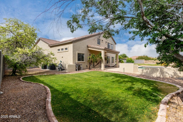 rear view of property featuring a yard, stucco siding, a fenced backyard, and a patio area
