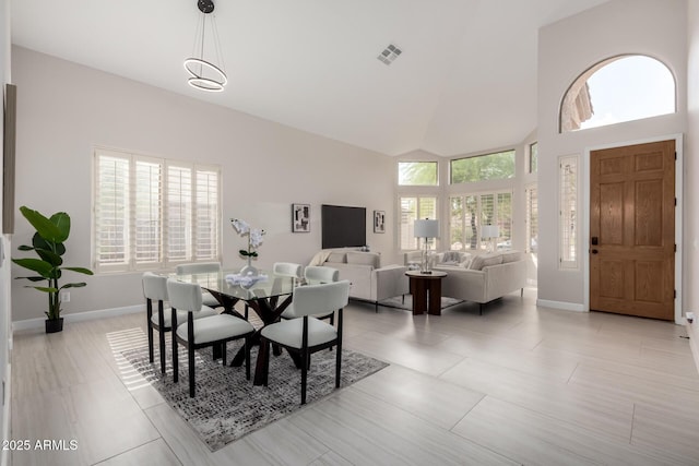 dining room with visible vents, baseboards, and high vaulted ceiling