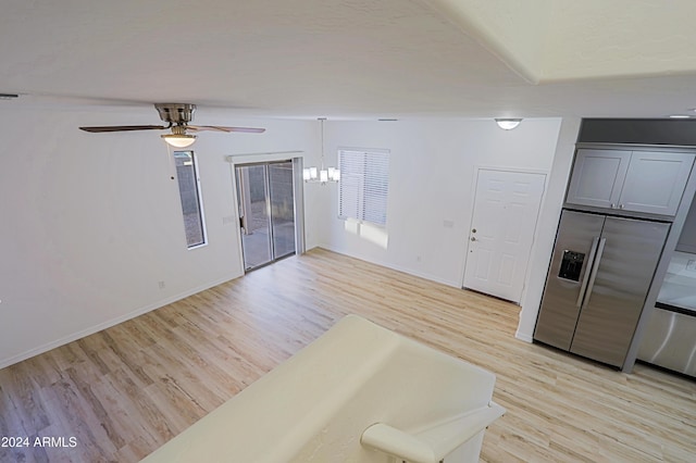 interior space featuring ceiling fan with notable chandelier and light hardwood / wood-style floors