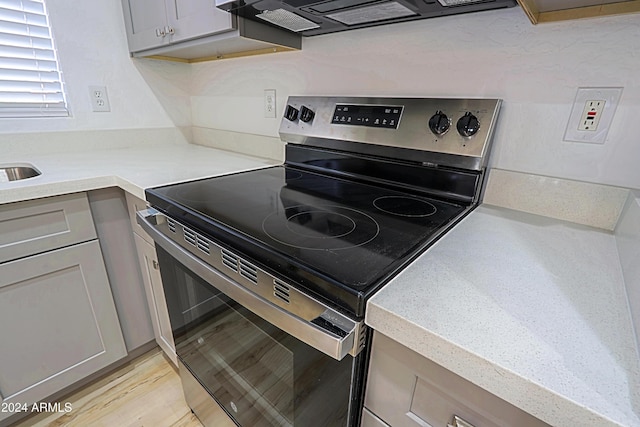 kitchen featuring stainless steel range with electric stovetop, gray cabinetry, and exhaust hood