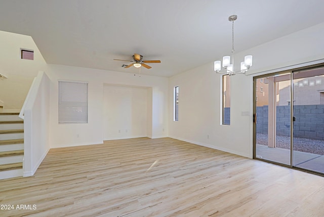 unfurnished living room featuring ceiling fan with notable chandelier, light hardwood / wood-style floors, and a healthy amount of sunlight