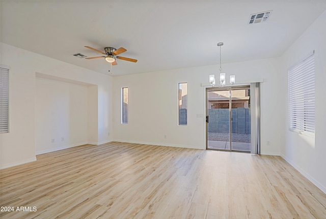 unfurnished room with ceiling fan with notable chandelier and light wood-type flooring