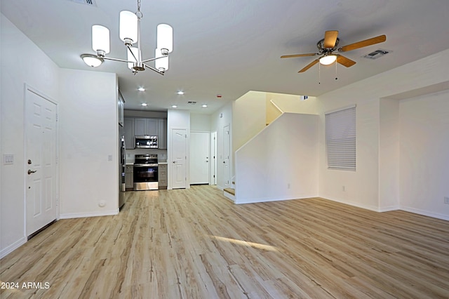 unfurnished living room featuring ceiling fan with notable chandelier and light hardwood / wood-style floors