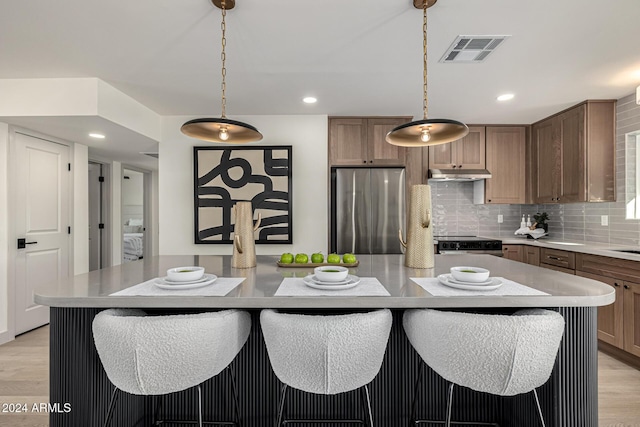 kitchen featuring pendant lighting, a center island, light wood-type flooring, and appliances with stainless steel finishes