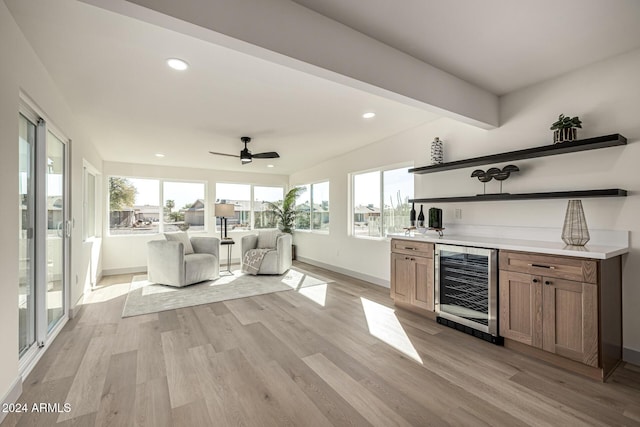 bar with wine cooler, ceiling fan, a healthy amount of sunlight, and light wood-type flooring