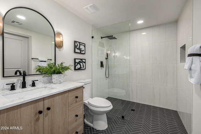 bathroom featuring tile patterned floors, vanity, tiled shower, and toilet