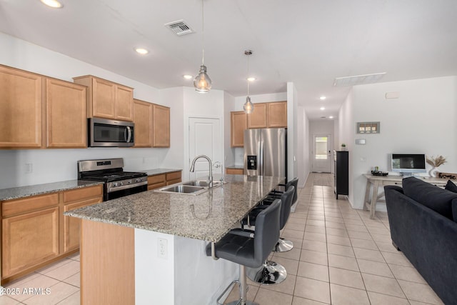 kitchen with visible vents, appliances with stainless steel finishes, a sink, light tile patterned floors, and open floor plan