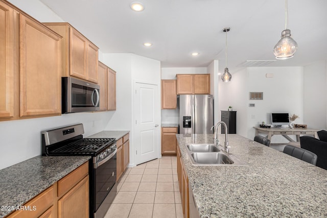 kitchen featuring pendant lighting, appliances with stainless steel finishes, a sink, light tile patterned floors, and open floor plan