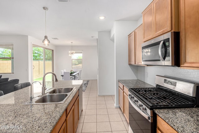 kitchen with decorative light fixtures, a sink, light tile patterned floors, a notable chandelier, and stainless steel appliances