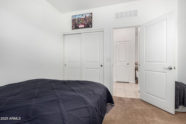 carpeted bedroom with visible vents, tile patterned flooring, and a closet