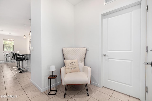 living area with visible vents, baseboards, light tile patterned floors, and a chandelier