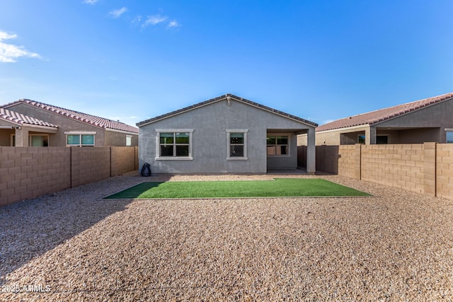 rear view of house featuring a yard, a fenced backyard, and stucco siding