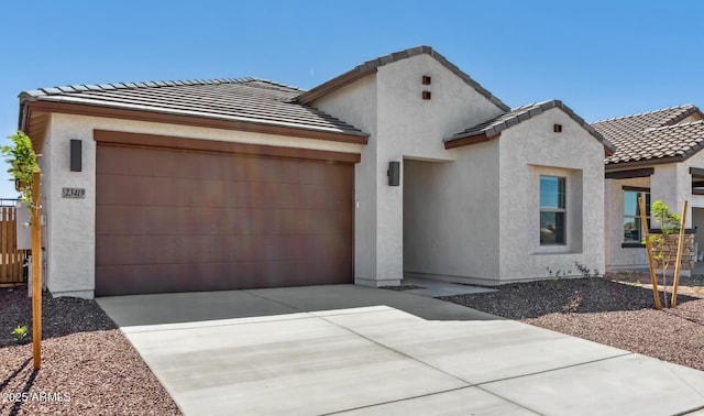 view of front of house featuring a garage, a tile roof, driveway, and stucco siding