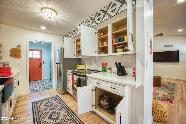 kitchen with decorative backsplash, white cabinetry, light hardwood / wood-style flooring, and stainless steel electric range