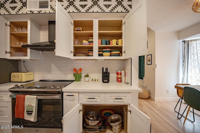 kitchen with stainless steel electric range oven, wall chimney exhaust hood, and white cabinetry