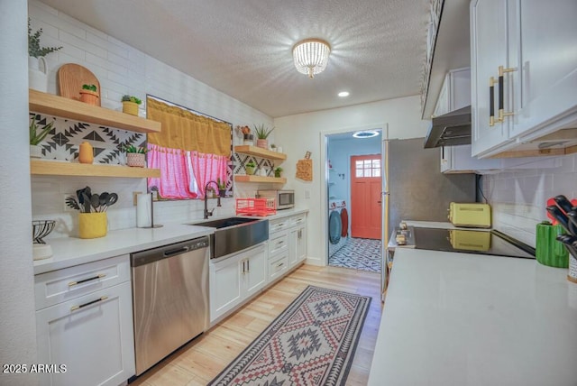 kitchen with a textured ceiling, white cabinets, sink, light hardwood / wood-style flooring, and stainless steel appliances