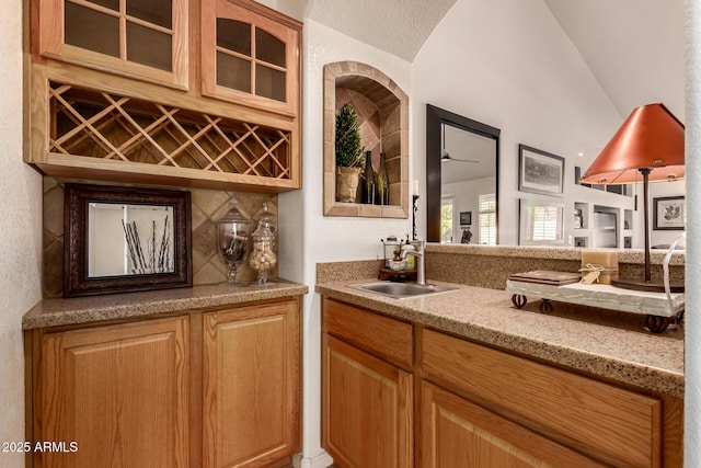 bar with light stone counters, sink, and ceiling fan